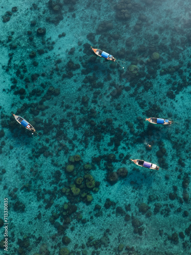 View from above, stunning aerial view of some long tail boats floating on a turquoise water. Phuket, Thailand.