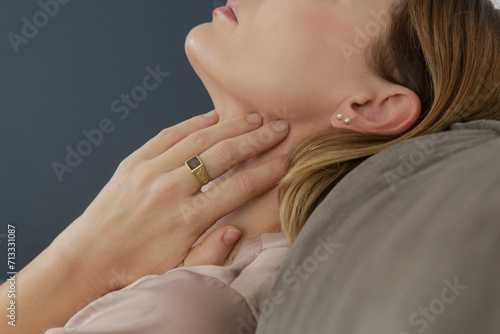 Caucasian woman touching her throat. Sore throat, cold, flu, tonsillitis or thyroid gland problem photo