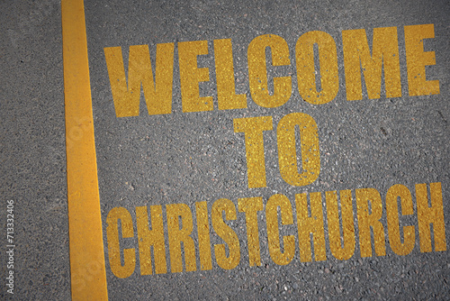 asphalt road with text welcome to Christchurch near yellow line.