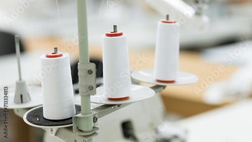 Close-up photo of three skeins of white thread on a sewing machine