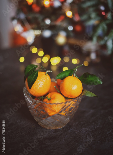 Tangerines in a crystal bowl against the background of New Year's lights. New Year's still life