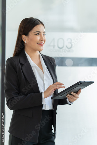 Young happy businesswoman working with tablet and document in corporate office.
