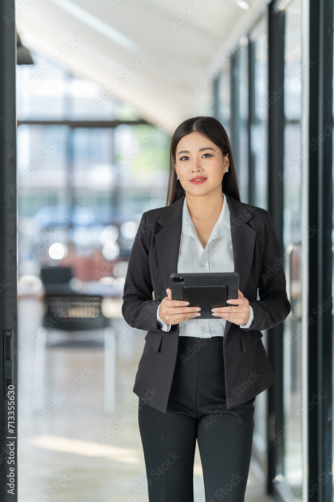 Portrait of beautiful young woman standing in front of glass board and smiling on camera. Female office worker using laptop in company. Portrait of beautiful young woman standing in front of glass board and smiling on camera. Female office worker using laptop in company.