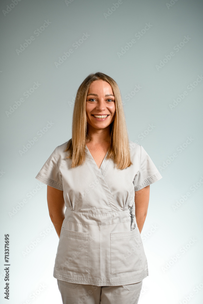 Pretty woman on a grey background with her hands behind her back Pretty woman on a grey background with her hands behind her back