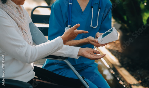 nurse with elderly man in wheelchair at park