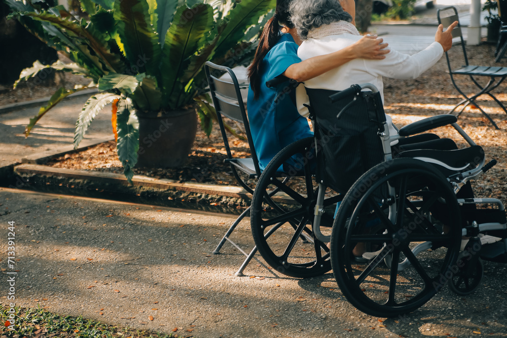 Obraz premium A nurse take care a senior male on wheelchair in his garden at home