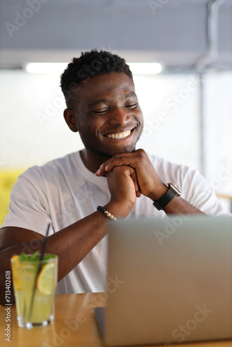 Smiling young businessman with a laptop, exuding happiness and professionalism in a modern office