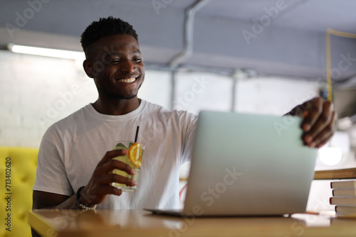 Confident young businessman working on a laptop, exuding happiness and professionalism in a modern office