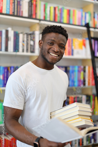 Happy young student in a library, surrounded by books and bookshelves, exuding positivity