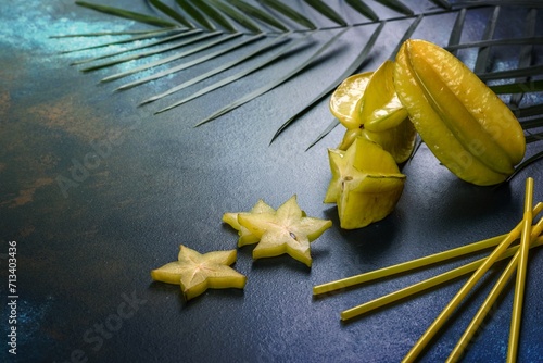 Fruit carambol, beach accessories and foliage of a tropical plant on colored paper photo