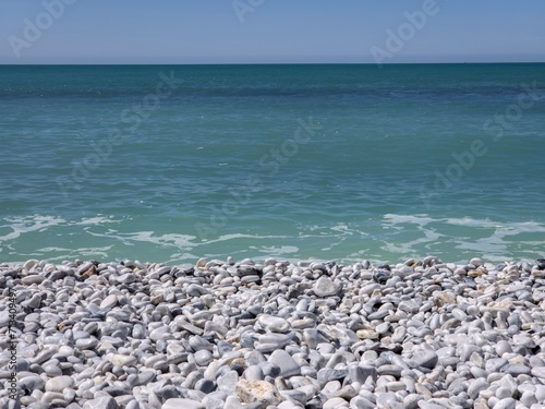 Pebble shore against a background of blue sea and blue sky