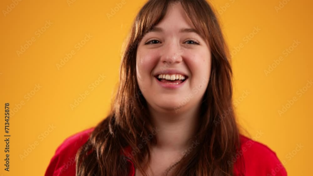 Portrait of attractive happy young woman 20s smiling and giving peace or victory sign gesture with hands isolated on yellow background in slow motion Portrait of attractive happy young woman 20s smiling and giving peace or victory sign gesture with hands isolated on yellow background in slow motion