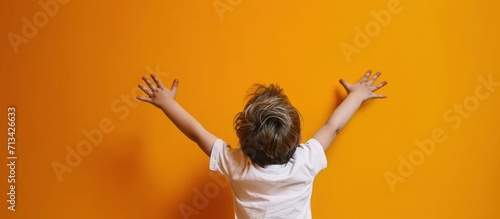 Portrait of happy little boy raised hands on yellow background