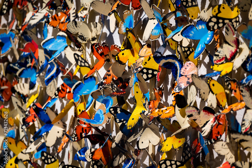 A wall of colorful butterflies made out of metal in the sun