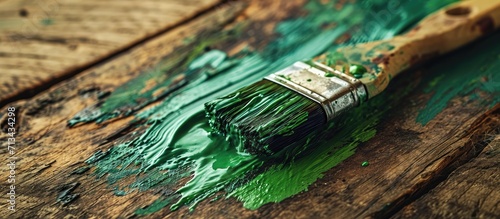 A close up of the bristles of a wide decorator s paint brush coated with green paint as it s used to paint a wood surface. Copy space image. Place for adding text