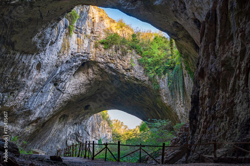 Giant cave with big holes in the sealing, all full of trees and water - Devetashka cave