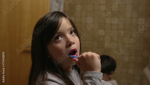 One little girl brushing teeth during night time routine. Child engaged in dental hygiene before bed