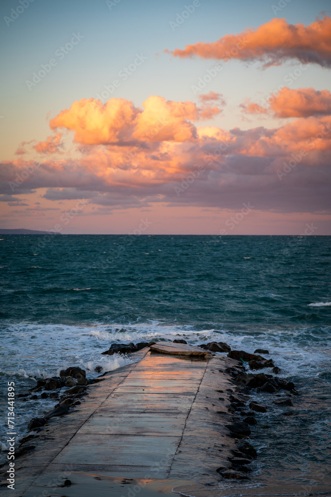 Sunset at the seaside with a walkway ramp and epic clouds