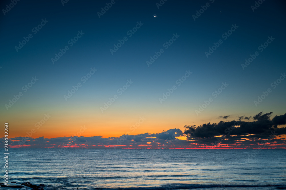 Early morning sea with stars, the moon, and clouds