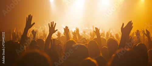 A concert crowd is bathed in a golden haze, hands raised in unison, capturing the collective euphoria of live music