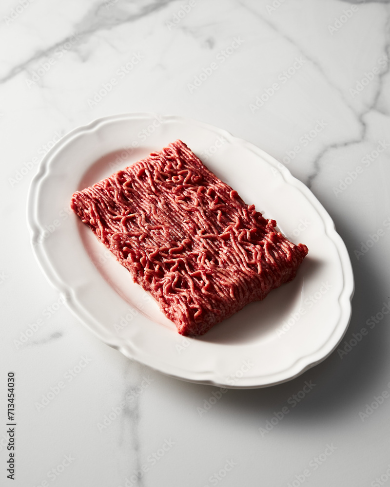 Raw and Fresh Minced Beef on white plate, white marble background. Minimalistic food photo, high-key. Raw and Fresh Minced Beef on white plate, white marble background. Minimalistic food photo, high-key.