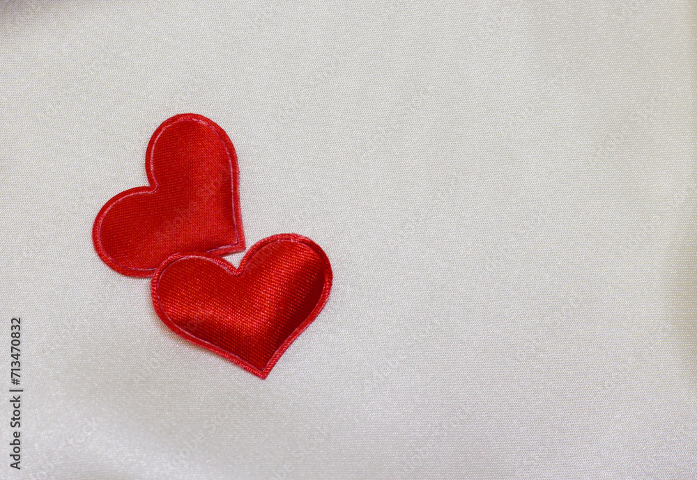 Pair of red hearts for Valentine's day on a background white silk close up Pair of red hearts for Valentine's day on a background white silk close up
