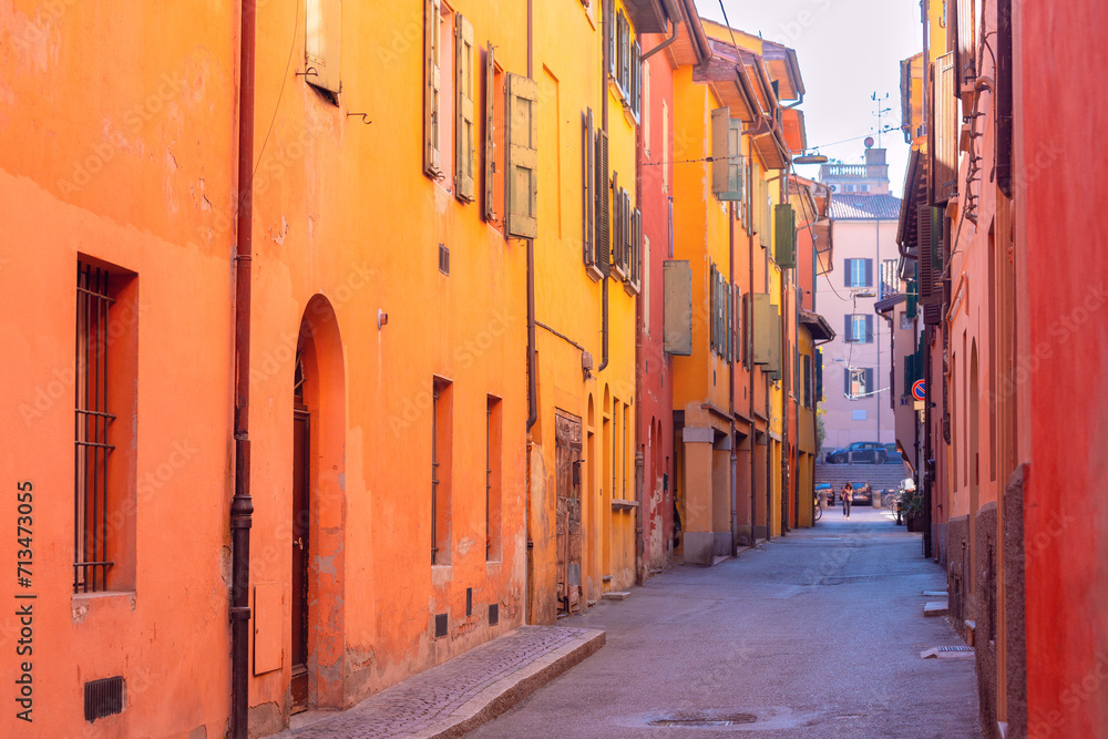 Bright multi-colored facades of old houses on a narrow street in Bologna.