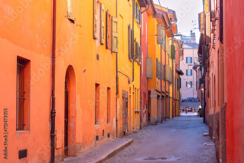 Bright multi-colored facades of old houses on a narrow street in Bologna.