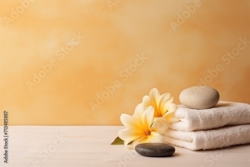  a stack of towels sitting on top of a table next to a pile of rocks and a flower on top of a table.