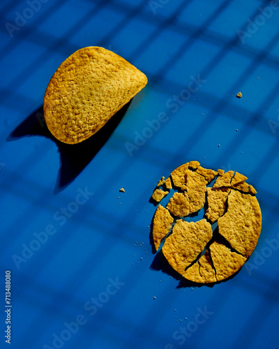 Golden and crusty potato chips on blue background. Minimalistic food photo. 