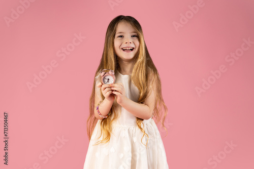 The best advertising concept for free time. Close-up portrait of confident, cute, charming, pretty, cute, gorgeous girl isolated on pink background with big alarm clock in hands, showing or giving.