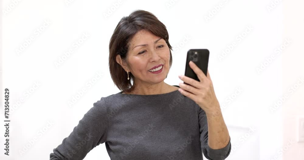 Closeup happy attractive woman smiling enjoying looking at mobile phone laughing talking using face time video chat studio lighting. Closeup happy attractive woman smiling enjoying looking at mobile phone laughing talking using face time video chat studio lighting.