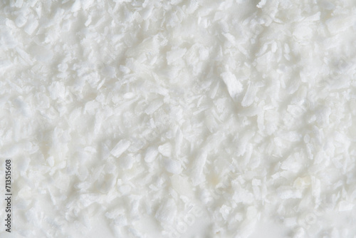 Background, coconut crumbs are sprinkled on a white glaze.