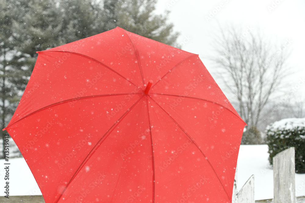 Closeup of a red umbrella while it is snowing - winter weather concept background