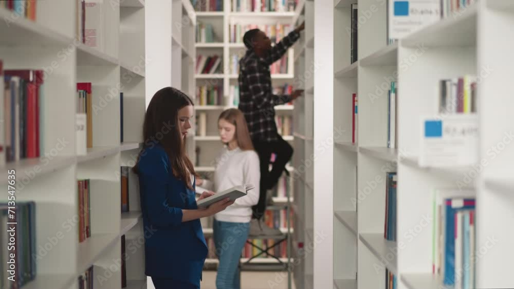 Students work with literature in public library. Young women read books and black man stands on step ladder in bookstore. College education Students work with literature in public library. Young women read books and black man stands on step ladder in bookstore. College education