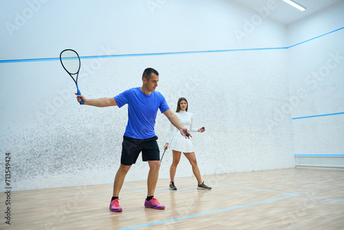 Man coach working with woman focuses on skill development during squash lesson © Viacheslav Yakobchuk