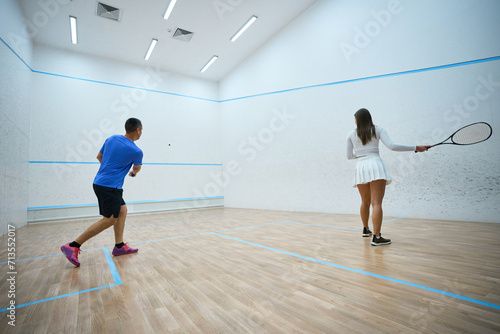 Woman athlete refines squash hitting techniques under man instructor's guidance