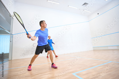 Fit men exercising on squash court promoting healthy lifestyle