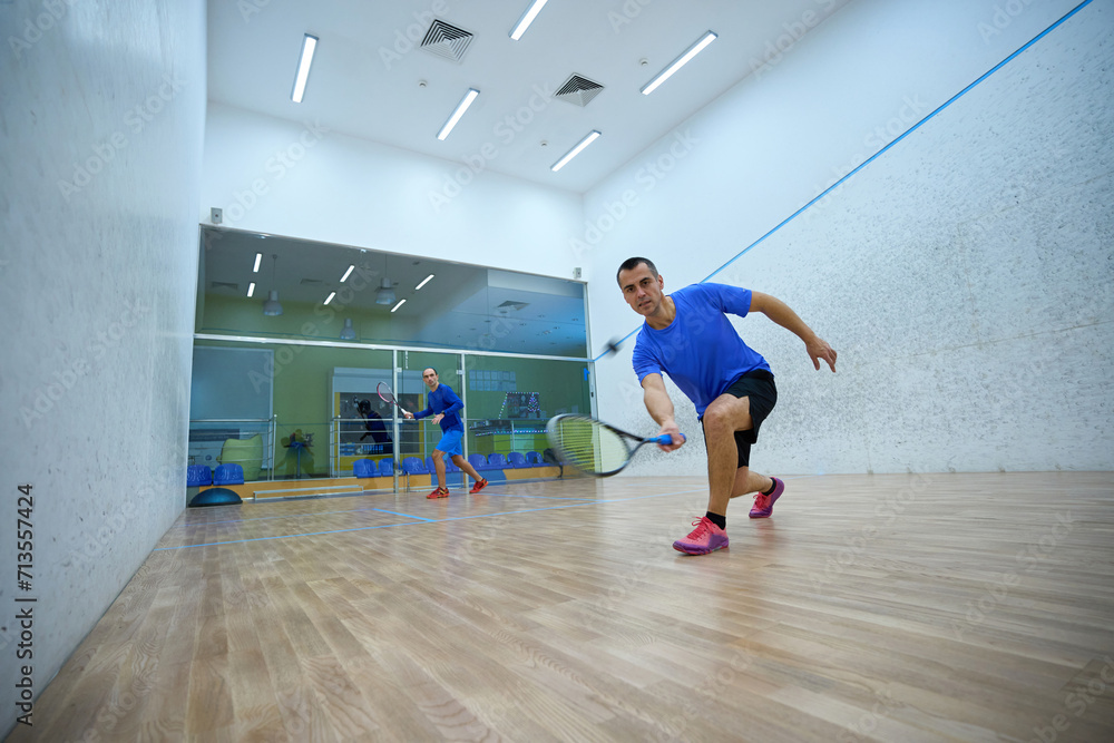 Athletic men challenging each other in squash enjoying the game Athletic men challenging each other in squash enjoying the game