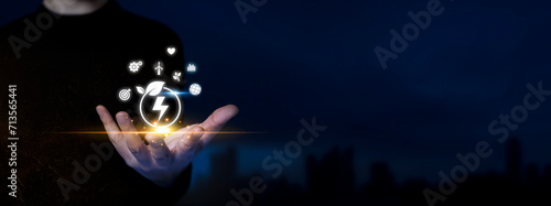 Green Energy: Man Holds Sustainable Icons. Eco-Friendly Solutions, Renewable Innovations on Virtual Green Energy Technology. Dark Blue City Background. photo