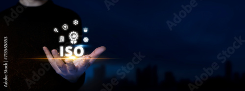 ISO. Man Holds Compliance Icons. Standardization, Quality Assurance on Virtual ISO Technology. Dark Blue City Background. photo