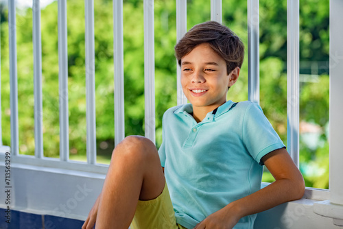 Handsome slyly smiling teenager's portrait on green garden background