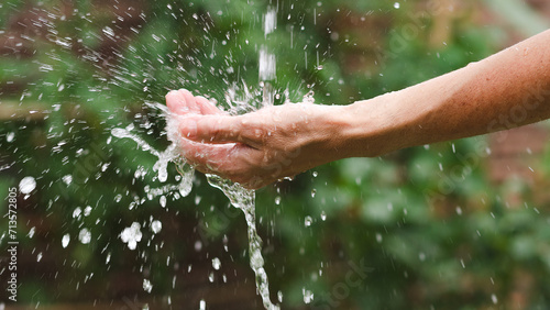 Woman's hand splashing water in the garden. Close up.