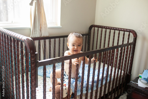 baby in a crib smiling no shirt with a diaper