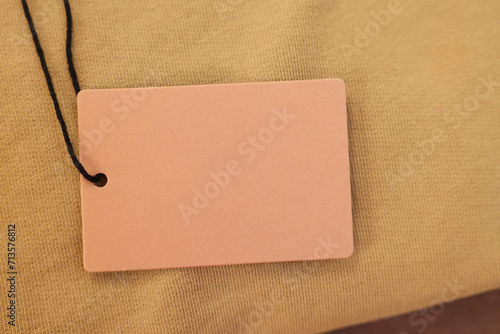 Cardboard tag on garment, closeup. Space for text