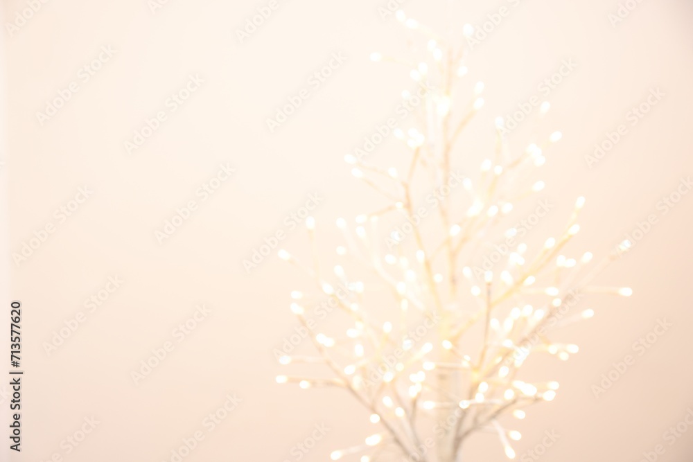 Decorative tree with lights on beige background, blurred view. Space for text Decorative tree with lights on beige background, blurred view. Space for text