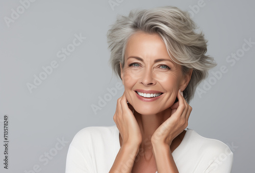 Stylish beautiful older woman with gray hair on a gray background