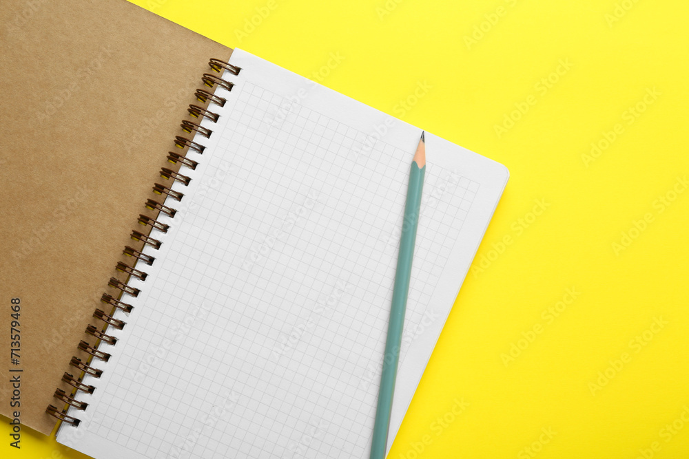 Notebook and pencil on yellow background, top view Notebook and pencil on yellow background, top view