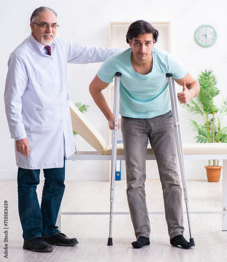 Young leg injured male patient visiting old doctor Young leg injured male patient visiting old doctor