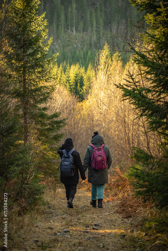 Two women going through forest in the mountains